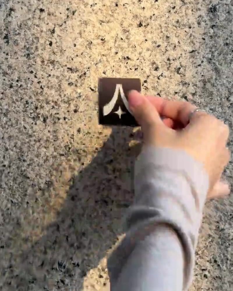 A hand placing the Asa Studio mark on a sunlit terrazzo wall