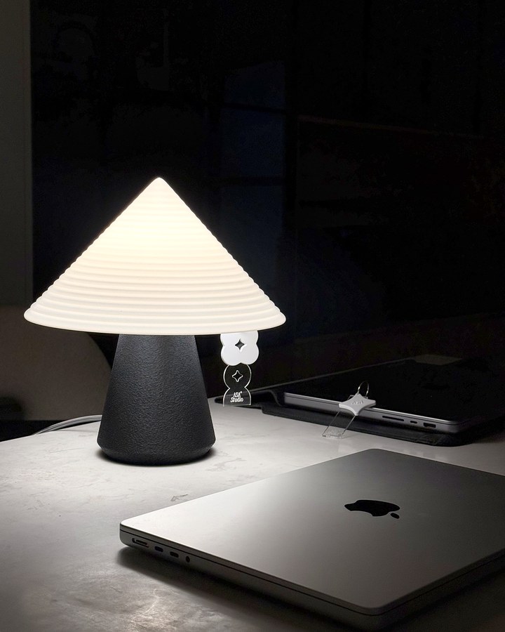 Black NOLA lamp glowing beside a MacBook and ASA charm on a late-night desk